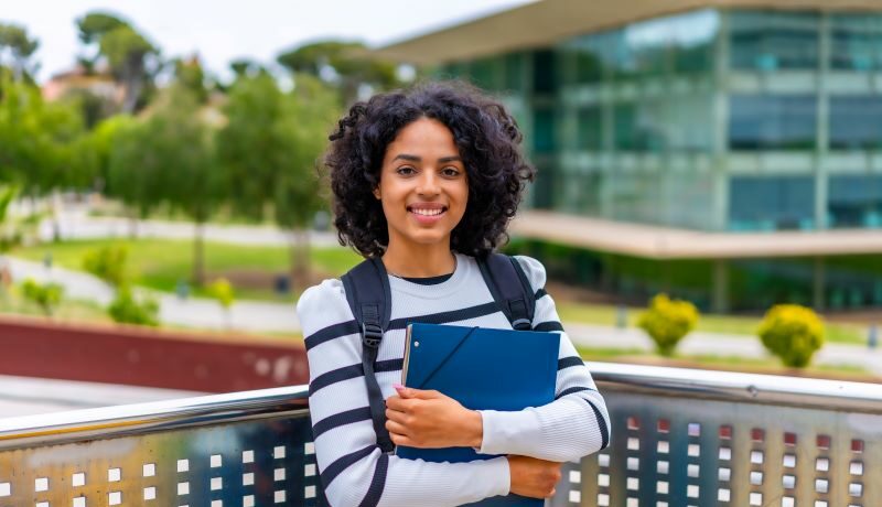 College student on campus holding books wearing backpack