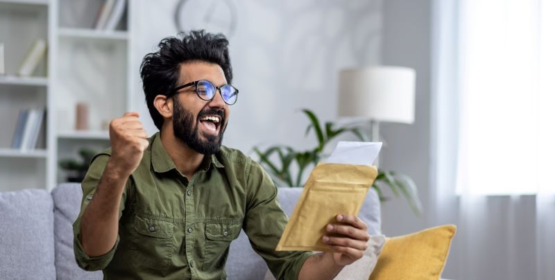 Man celebrating while reading letter on sofa