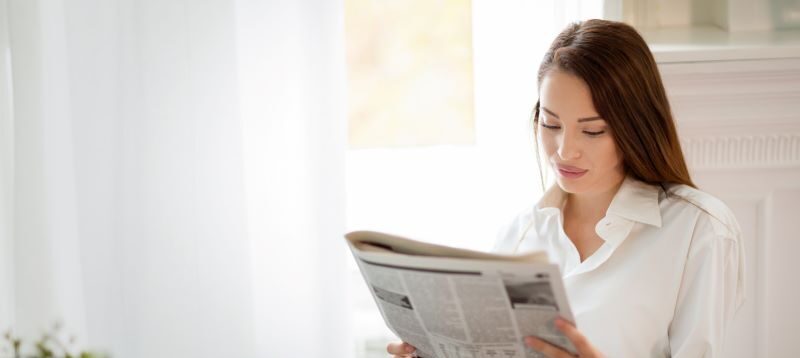 Woman reading paper at kitchen table